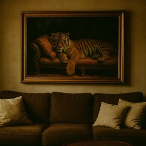 Puede incluir: Un cuadro enmarcado de un tigre descansando en una chaise longue cuelga sobre un sofá marrón con cojines color crema. El tigre tiene rayas naranjas y negras. Una planta en maceta se encuentra a la derecha del sofá, contra una pared verde apagada.