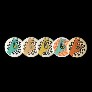 Könnte beinhalten: Eine Sammlung von fünf runden Knöpfen mit einer Handgeste mit einem Auge in der Handfläche. Jeder Knopf hat ein anderes Farbschema: Türkis, Hellbraun, Gelb, Türkis-Orange und Orange. Das Hintergrunddesign ist ein Schachbrettmuster.