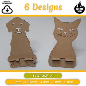 Può includere: Due supporti per telefono in legno a forma di animale. Uno è un cane, l'altro un gatto. Il cane e il gatto sono marrone chiaro con dettagli ritagliati. L'immagine include il testo "6 Designs", "SVG - DXF - AI" e misure di 3 mm - 1/8 inch - 4 mm - 5 mm - 6 mm.