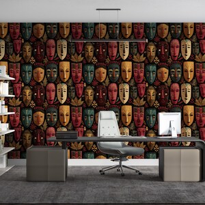 May include: A home office with a dark patterned wallpaper featuring repeating tribal masks in red, green, gold, and brown. The room includes a desk, chair, and shelving unit, creating a workspace with a cultural theme.