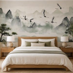 May include: A bedroom featuring a large wall mural depicting a misty mountain landscape with flying cranes and pine trees in shades of green, gray, and white. The room includes a wooden bed frame with white bedding, two wooden nightstands, and lamps.