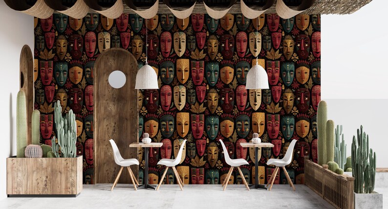 May include: Interior design featuring a wall covered in a repeating pattern of colorful tribal masks. The room includes white chairs, small tables, and hanging pendant lights. Wooden archways and a planter with cacti add to the decor.