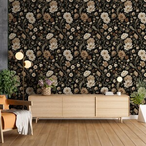 May include: A room interior featuring a floral wallpaper in black, beige, and brown tones. A wooden cabinet, an orange armchair, and a floor lamp are in front of the wallpaper. The room has a wooden floor and a gray wall.