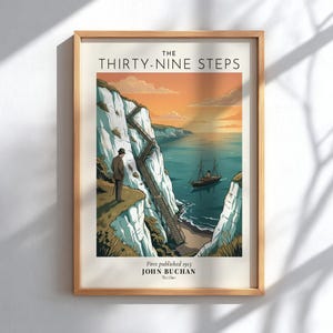 May include: A framed art print titled The Thirty-Nine Steps by John Buchan. The illustration depicts a person in a hat standing on white cliffs overlooking a sea with a small boat, featuring a wooden staircase descending the cliffside.