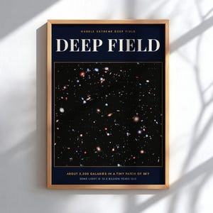May include: A framed poster titled DEEP FIELD featuring the Hubble Extreme Deep Field image. The dark blue background displays numerous colorful galaxies. Text reads: ABOUT 5,500 GALAXIES IN A TINY PATCH OF SKY, SOME LIGHT IS 13.2 BILLION YEARS OLD.