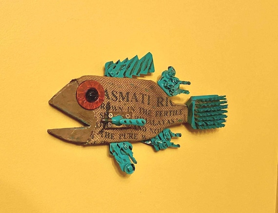 A sculptural wall fish built from upcycled burlap, turquoise, and found materials — the kind of eccentric, one-of-a-kind nautical art that stops guests mid-conversation.
