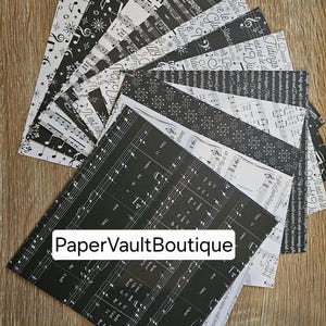 May include: A collection of 12 black and white patterned scrapbook paper sheets featuring musical notes, snowflakes, and other festive designs. The paper is labelled "PaperVaultBoutique".