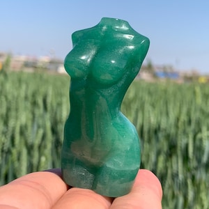 Peut inclure: Une sculpture de torse féminin en jade vert. La sculpture est lisse et polie, avec une qualité translucide. C'est un objet décoratif qui pourrait être utilisé dans une maison ou un bureau.
