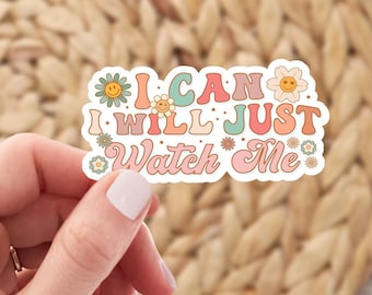 May include: A colorful sticker with the text "I CAN I WILL JUST WATCH ME" in a retro font. The sticker is decorated with flowers and smiley faces.