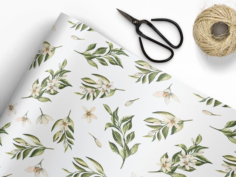 May include: White wrapping paper with a repeating pattern of green leaves and white flowers. The paper is rolled up and partially unrolled, revealing the pattern.