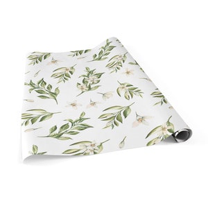 May include: White wrapping paper with a repeating pattern of green leaves and white flowers.