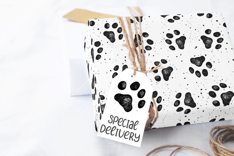 Pu&ograve; includere: Carta da regalo bianca con un motivo a impronte di zampa nere e un'etichetta regalo bianca con un'impronta di zampa nera e il testo "Consegna speciale".