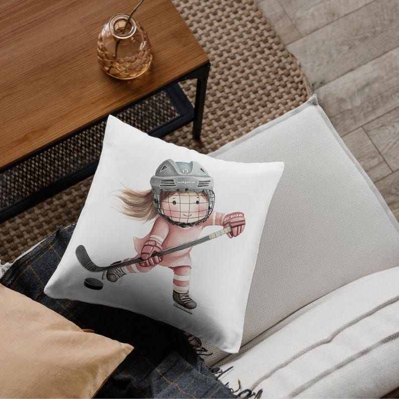 May include: White throw pillow with a watercolor illustration of a girl wearing a hockey helmet and holding a hockey stick. The girl is wearing a pink jersey and has brown hair.