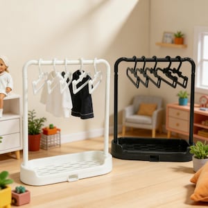 May include: Miniature white and black clothing rack with hangers. The white rack holds white and black doll clothes. The black rack holds black doll clothes. The racks have a tray at the bottom. A doll sits on a white shelf.