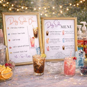 May include: Two framed signs with gold trim display a "Dirty Soda Bar" menu. The menu includes drink recipes and instructions. Several glasses of soda are visible, along with ingredients like fruit, ice, and syrups. The background features string lights.