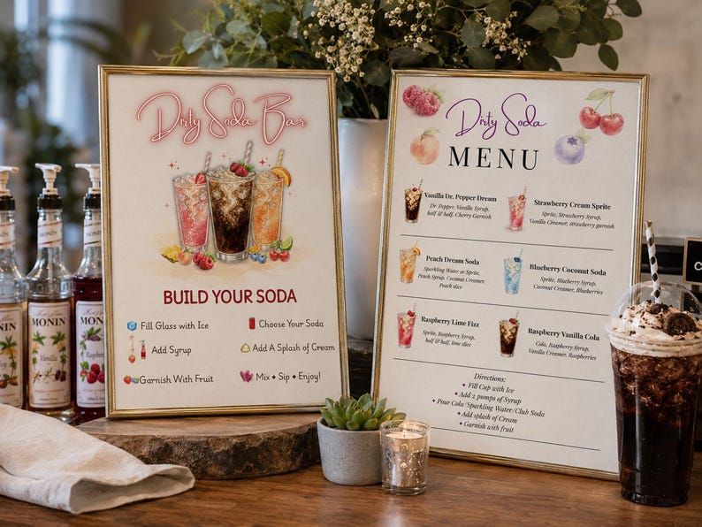 May include: Two framed signs for a Dirty Soda Bar and Menu with gold frames. The signs feature illustrations of soda drinks, fruit, and instructions for building a soda. The menu lists various soda combinations with ingredients and directions.