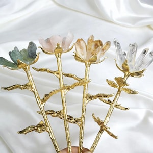 May include: Four decorative flower-shaped hair accessories. Each features a different colored crystal bloom atop a gold-colored stem. The crystals are green, pink, yellow, and clear. The stems have a detailed, branch-like design.