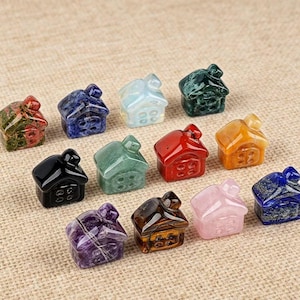 May include: A collection of small, gemstone house figurines in various colors, including green, red, and blue. Each house has a chimney and windows, and they are arranged on a neutral-toned surface.