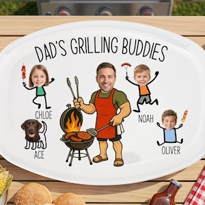 May include: Oval white platter with the text "Dad's Grilling Buddies" and cartoon illustrations of a man, three children, and a dog. The man is grilling burgers. Corn on the cob, salad, and buns are also visible.