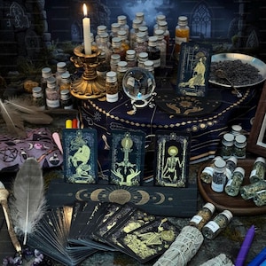 May include: A mystical scene featuring tarot cards, glass bottles filled with herbs, a lit candle in a gold holder, a crystal ball, and a feather. The cards have gold and teal designs. The scene is set on a dark blue cloth.