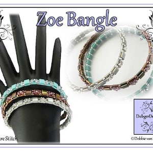 Può includere: Quattro braccialetti di perline in turchese, argento, marrone e viola. I braccialetti sono impilati su un manichino di mano nero. I braccialetti sono chiamati "Zoe Bangle" e sono realizzati con punto quadrato. L'immagine include il testo "DebbiegerDesigns" e "Debbie van Tonder".