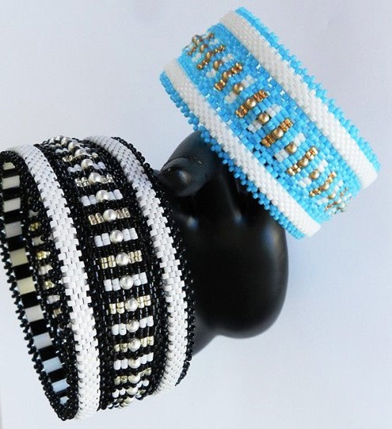 Op de afbeelding: Twee kralenarmbanden, een zwart-wit met zilveren accenten en een blauw-wit met gouden accenten.