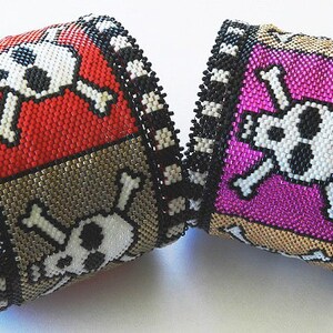 Puede incluir: Dos pulseras de cuentas con dise&ntilde;os de calavera y huesos cruzados. Una pulsera es roja, negra y blanca, y la otra es rosa, negra y blanca.