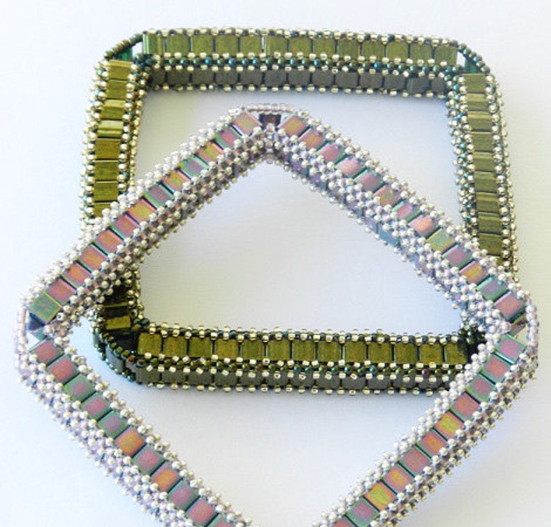 May include: Two square-shaped beaded bracelets, one is a light green and silver color, and the other is a light purple and silver color. The bracelets are stacked on top of each other.