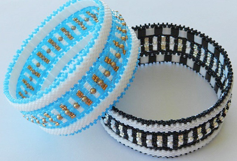 Op de afbeelding: Twee kralenarmbanden, een met een blauw-wit geruit patroon met gouden accenten en de andere met een zwart-wit geruit patroon met zilveren accenten.