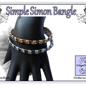 May include: Two beaded bracelets on a hand. The top bracelet is gold with blue beads. The bottom bracelet is dark blue with silver beads. The bracelets are called "Simple Simon Bangle" and are made by DebbgerDesigns.