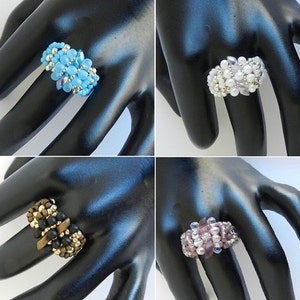 May include: Four beaded rings in different colours and styles. The rings are made with small beads in a variety of colours, including blue, white, black, and purple. The rings are all different sizes and shapes.
