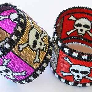 Puede incluir: Dos pulseras de cuentas con un dise&ntilde;o de calavera y huesos cruzados. Una pulsera es roja, blanca y negra, y la otra es rosa, dorada y negra.