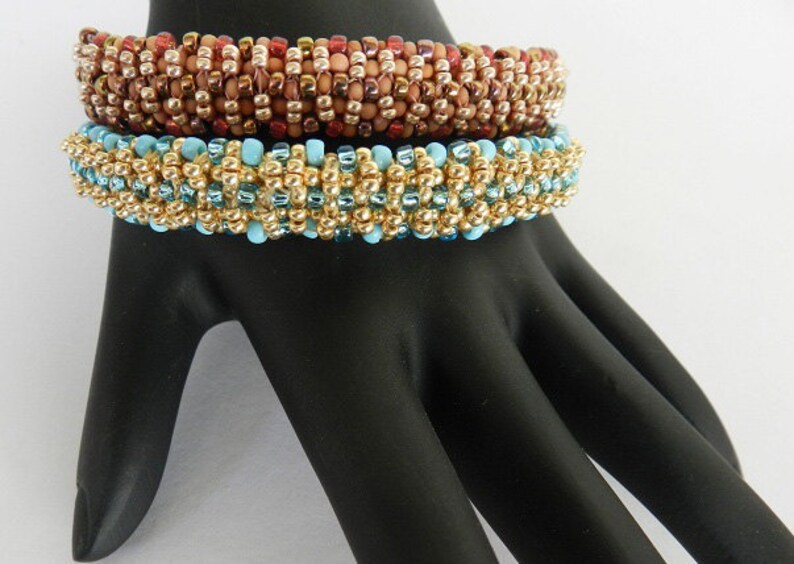 Puede incluir: Tres pulseras de cuentas apiladas en un maniqu&iacute; de mano negro. La pulsera superior es marr&oacute;n y dorada, la pulsera del medio es dorada y azul, y la pulsera inferior es dorada y azul.