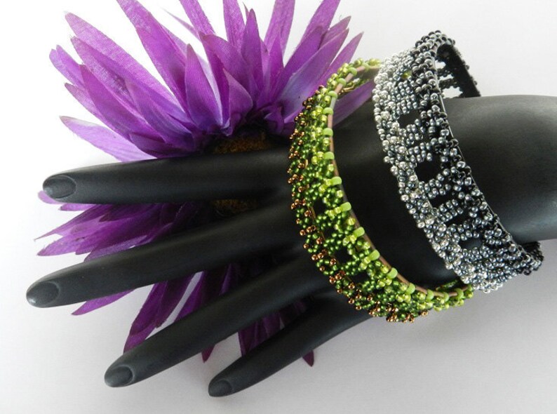 Puede incluir: Tres pulseras de cuentas en un maniqu&iacute; de mano negro. Las pulseras son verdes, marrones y plateadas con cuentas negras. Las pulseras est&aacute;n apiladas unas sobre otras.