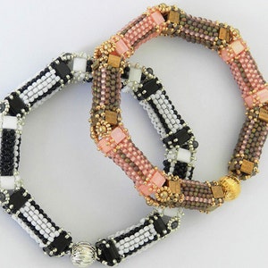 Peut inclure: Deux bracelets en perles, l'un noir et blanc, l'autre rose, brun et or. Les deux bracelets ont une perle ronde &agrave; l'extr&eacute;mit&eacute;.