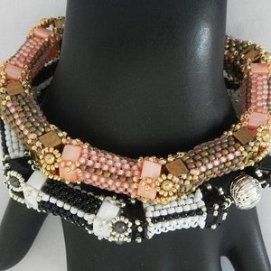 Peut inclure: Un ensemble de trois bracelets en perles avec un motif noir et blanc, un motif rose et marron et un charme argent&eacute;.