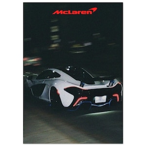 Könnte beinhalten: Ein weißer McLaren-Sportwagen mit roten und blauen Akzentlichtern wird nachts in Bewegung gezeigt. Das McLaren-Logo ist rot oben. Die Rücklichter des Autos leuchten, und das Nummernschild ist sichtbar.