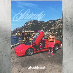 Könnte beinhalten: Ein pinkfarbener Lamborghini Diablo Cabriolet, das auf einer Straße mit Blick auf ein Gewässer geparkt ist. Ein Mann in pinken Shorts und einem weißen Tanktop steht neben dem Auto. Der Text "Shiny" und "la dolce vita" ist in Weiß auf dem Bild geschrieben.