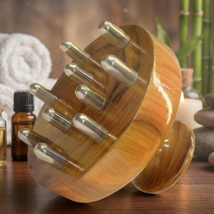 Può includere: Un massaggiatore per la testa in legno con punte metalliche argentate. Il massaggiatore ha un manico curvo e una finitura lucida. Lo sfondo include asciugamani bianchi arrotolati, bottiglie di oli essenziali e steli di bambù.