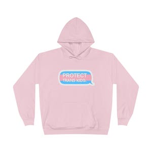 Puede incluir: Sudadera con capucha rosa con una burbuja de diálogo azul y rosa que dice "PROTECT TRANS KIDS."
