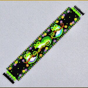 May include: A beaded bracelet featuring a black background with a repeating pattern of green chameleons and colorful flowers. The bracelet has a rectangular shape with a clasp closure. The chameleons are detailed with white, green, and brown accents.