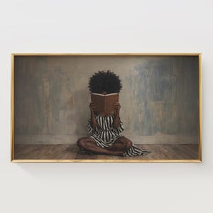 May include: Framed art print featuring a person seated on a wooden floor, reading a book. The person is wearing a black and white striped dress. The background is a muted blue and gray wall. The frame is gold.
