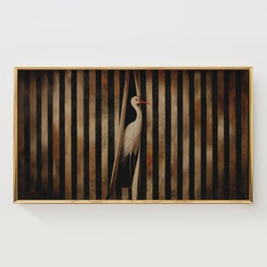 May include: A framed artwork featuring a white stork with a red beak, standing behind a vertical striped background of black, brown, and tan. The artwork has a gold frame and is mounted on a white wall.