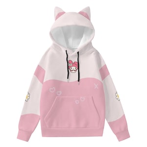 May include: A white and pink hooded sweatshirt with cat ears on the hood. The sweatshirt features a pink pocket, a cartoon character, and heart and flower graphics. The sleeves have pink accents and flower graphics.