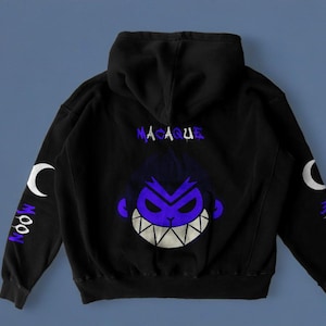 Op de afbeelding: Zwarte hoodie met een paarse en witte afbeelding van een apenkop met de tekst "MACAQUE" en "MOON" op de mouwen.