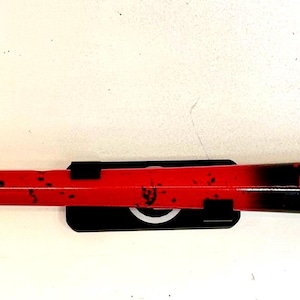 May include: A baseball bat with a red handle and a black barrel. The bat has a red grip and a black label. The bat is approximately 34 inches long.
