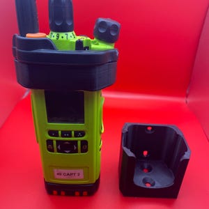 Pu&ograve; includere: Una radio a due vie con corpo verde lime, dettagli neri e una base di ricarica nera abbinata. La radio ha uno schermo e diversi pulsanti. L'etichetta sulla radio recita "48 CAPT 2".