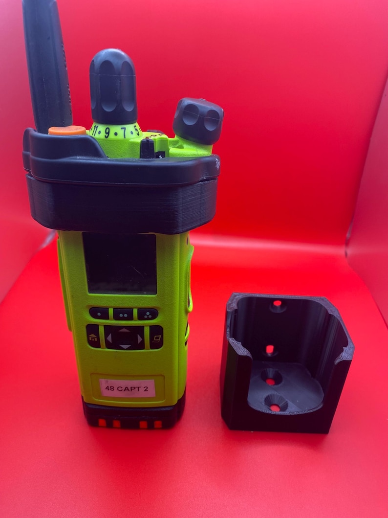 Pu&ograve; includere: Una radio a due vie con corpo verde lime, dettagli neri e una base di ricarica nera abbinata. La radio ha uno schermo e diversi pulsanti. L'etichetta sulla radio recita "48 CAPT 2".