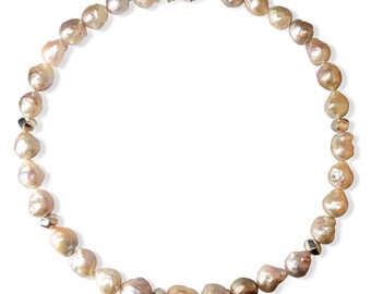 May include: A necklace made of light pink baroque pearls with silver accents. The pearls are strung on a silver chain with a lobster clasp.