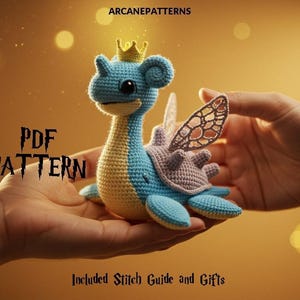 Puede incluir: Una criatura marina azul y amarilla tejida a ganchillo con una corona y alas se sostiene en dos manos. Se muestra el texto "PDF PATTERN", junto con "Included Stitch Guide and Gifts". La imagen tiene un fondo cálido y dorado.